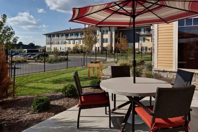 A patio with a table and chairs under a striped umbrella  at The Piper, Kansas City, KS.